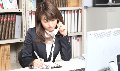 写真:電話をしながらメモをとっている女性