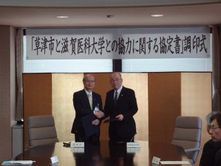 写真：握手をする草津市長と塩田学長