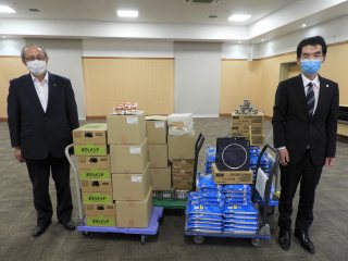 届いた食料品と上本学長、松浦理事 写真:届いた食料品と上本学長、松浦理事